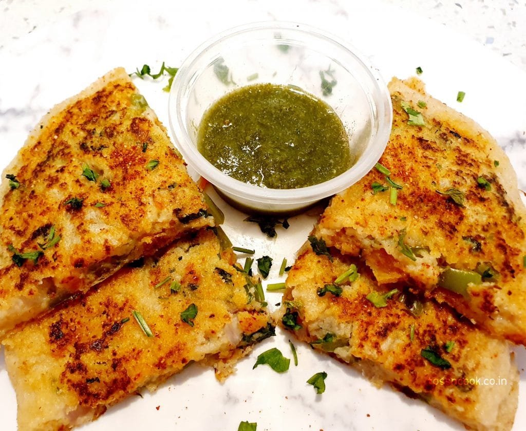 Top view image of four pieces of Sandwich Uttapam served with green chutney