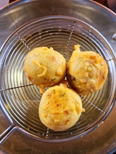 Batata vada fried in oil and the oil being strained using a strainer