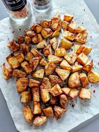 Air fryer salt and pepper potatoes on a white butter paper with the salt and pepper in the background
